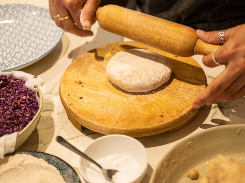 Hands holding a rolling pin above bread dough